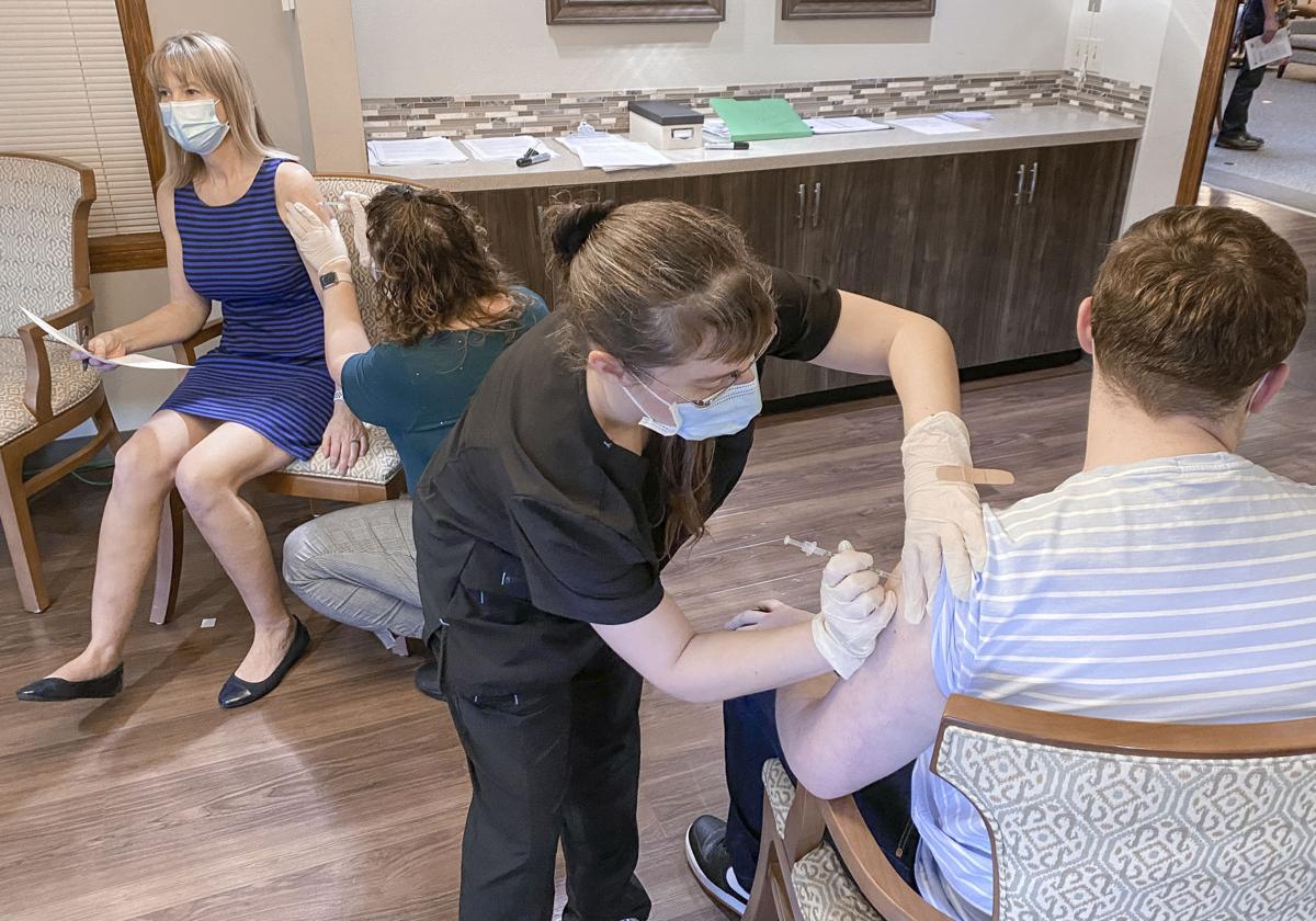 Laura Foster (front) vaccinates Colton Peach while Caroline Davis (back) vaccinates Sandra Jensen on Wednesday at Country Meadow Village in Sedro-Woolley.