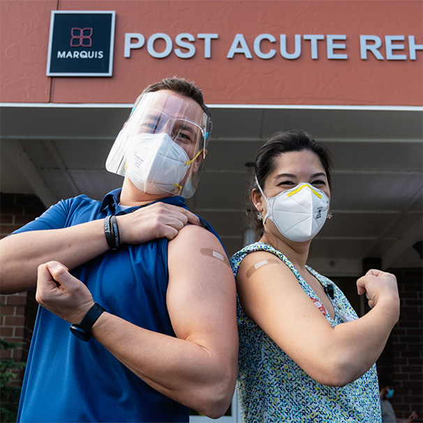 Consonus Pharmacy employees pose back to back to show off their vaccine bandages.
